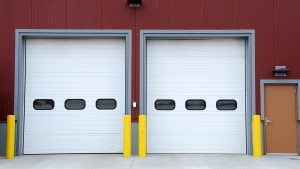 White commercial garage doors with window panels in loading area of red building