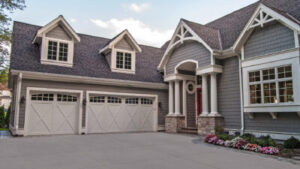 Upscale home with three-car garage that has matching single and doublewide door with decorative barn detail. 